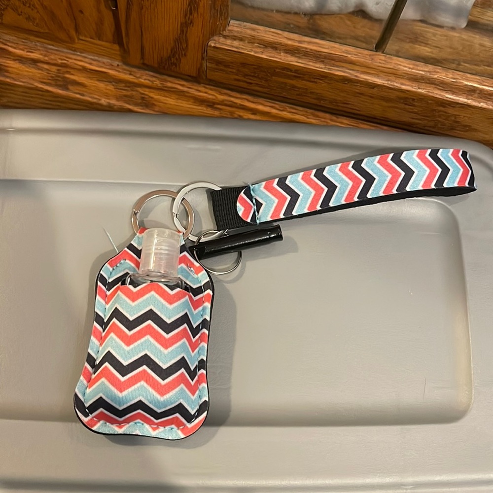 Hand sanitizer holder with safety whistle